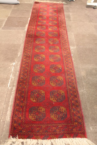 An Afghan style red ground runner with 28 octagons to the centre 155" x 32 1/2"