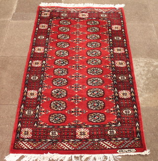 A red ground Bokhara rug with 22 octagons to the centre, signed,  63" x 37"