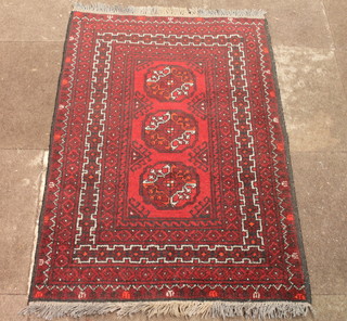 A red ground Afghan rug with 3 octagons to the centre within  multi-row borders 47" x 31"