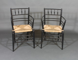 A pair of William Morris style ebonised stick and rail back  carver chairs with woven rush seats