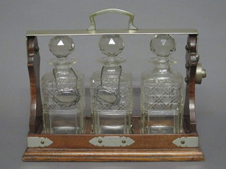 An oval silver plated 3 bottle tantalus, bottle chipped, together  with 2 plated decanter labels
