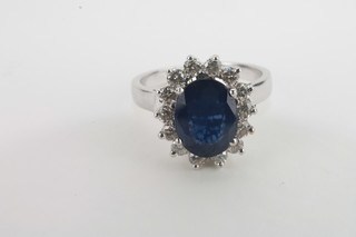 A lady's white gold dress ring set an oval cut sapphire  surrounded by diamonds