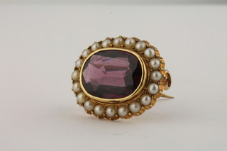 A gilt brooch set an oval cut amethyst supported by diamonds