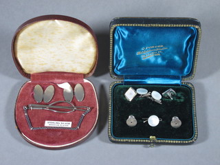 A pair of mother of pearl cufflinks and studs together with a set  of oval silver cufflinks and ditto tie retainer