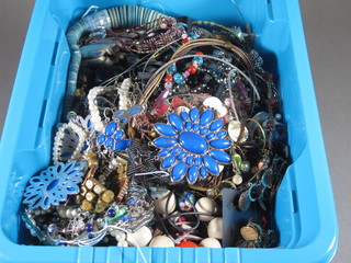 A blue plastic crate containing a collection of costume jewellery