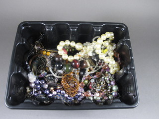 A black plastic crate containing a collection of costume jewellery