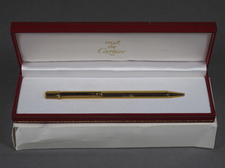 A Cartier ball point pen contained in a reeded gold plated case,  cased