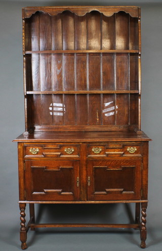A carved oak Jacobean style dresser with raised back fitted 2 shelves, the base fitted 2 drawers above a double cupboard raised  on turned and block supports 42"