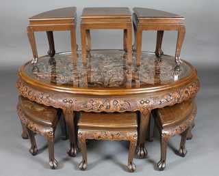 An oval carved Oriental hardwood table with 6 interfitting stools, raised on cabriole supports 49"