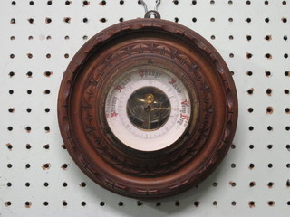 An aneroid barometer with paper dial contained in a circular carved walnut case 6"