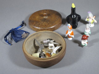A turned wooden bowl containing a pottery pie lifter, various thimbles and other curios