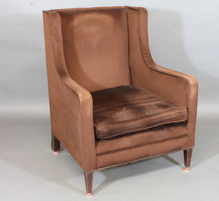 An Edwardian mahogany wing chair upholstered in brown  material