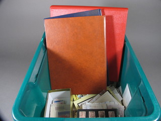 A blue stock book of stamps, a brown stock book of stamps, an album of stamps and a green crate containing a collection of  stamps