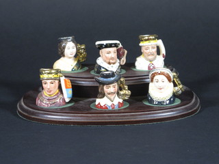 A set of 6 tiny Royal Doulton limited edition Kings and Queens  of the Realm character jugs - Henry V, Henry VIII, Elizabeth I,  Charles I, Victoria and Edward VII bases marked D6993 number  172 1 1/2", complete with wooden stand   ILLUSTRATED