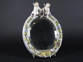 A 19th Century oval bevelled plate wall mirror contained in a Dresden style floral encrusted frame supported by 2 cherubs 11"