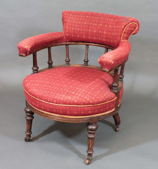 A Victorian walnut tub back armchair with spindle decoration, raised on turned & fluted supports