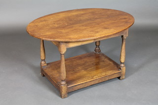 An oval oak 2 tier occasional table raised on turned and block supports 36"
