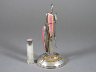 An Art Deco silver and enamelled 3 piece manicure set  comprising file, buffer and nail cleaner, raised on a matching  stand, Birmingham 1925 and a pair of associated steel scissors  and a salts bottle