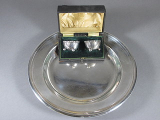 A pair of cased silver plated salts and a circular silver plated hotelware dish