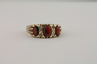 A 9ct gold dress ring set 3 oval garnets supported by diamonds