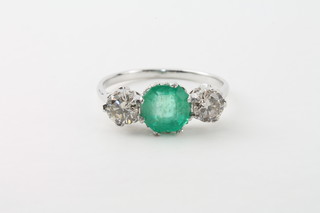An 18ct gold dress ring set an emerald supported by diamonds