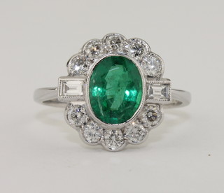 An 18ct gold dress ring set an oval cut emerald supported by  diamonds