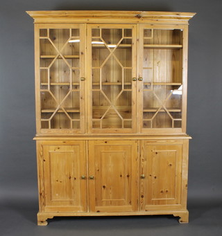 A Georgian style pine bookcase on cabinet with moulded and  dentil cornice, triple cupboards fitted adjustable shelves enclosed  by astragal glazed panelled doors, the base fitted triple  cupboards, raised on bracket feet 60"