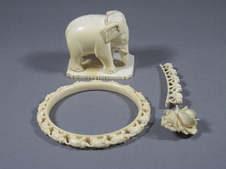 A carved ivory figure of a standing elephant 2", a carved bracelet decorated elephants, a bridge of elephants brooch and a floral  ivory brooch