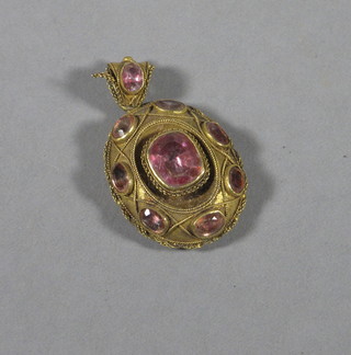 A gilt metal oval locket pendant set pink stones