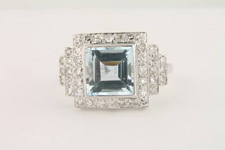 An 18ct gold dress ring set a square cut aquamarine surrounded by diamonds