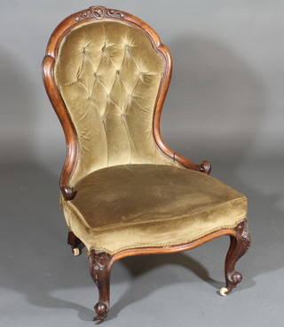A Victorian mahogany show frame nursing chair upholstered in  green material, raised on cabriole supports