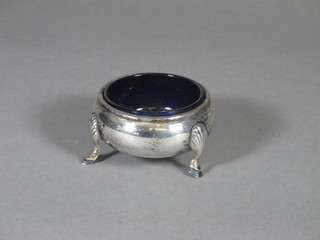A circular silver salt with blue glass liner, raised on hoof feet, London 1929, 2 ozs