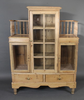A Continental pine cabinet the centre section fitted shelves enclosed by panelled doors flanked by a gallery above 2  cupboards enclosed by panelled doors, the base fitted 2 long  drawers, raised on turned supports 49"