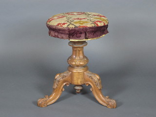 A Victorian carved walnut adjustable piano stool, raised on  carved tripod base