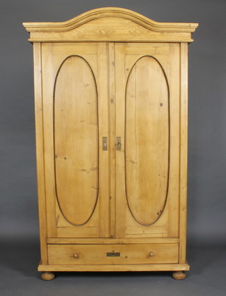 A Continental stripped and polished pine cabinet with moulded cornice, the interior fitted shelves enclosed by oval panelled  doors, the base fitted a drawer, 46"