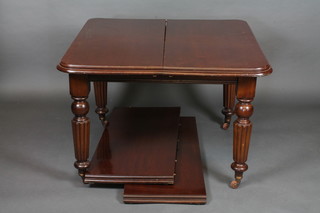 A mahogany extending dining table raised on turned and reeded supports with 2 extra leaves