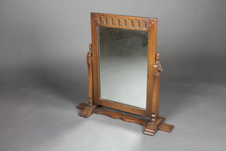 A rectangular plate dressing table mirror contained in an oak frame with arcaded decoration