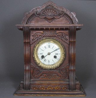 A Victorian Continental striking bracket clock with enamelled  dial and Roman numerals contained in a carved oak case