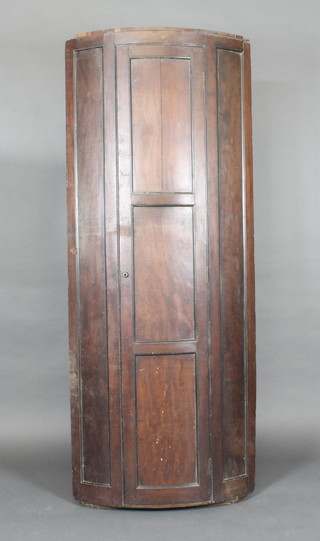 A 19th Century mahogany bow front hanging corner cabinet, the  interior fitted shelves enclosed by a panelled door 26"