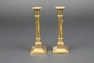 A pair of brass candlesticks raised on square spreading feet 9"