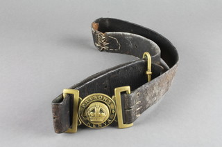A leather belt with brass buckle marked Prisons Kenya