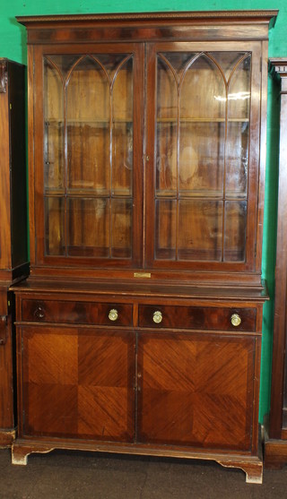 An Edwardian mahogany bookcase on cabinet, the upper section  with inlaid cornice, fitted adjustable shelves enclosed by astragal  glazed panelled doors, the base fitted 2 long drawers above a  double cupboard, raised on bracket feet 48"