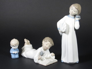 A Nao figure of a standing girl with alarm clock 9", a Nao figure of a boy reading a book with dog 6" and a Nao style figure of a  boy reading a book 3"