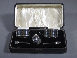 A 5 piece pierced oval silver condiment set comprising mustard, salt, pepper pot and 2 condiment spoons, Birmingham 1914,  complete with blue glass liners, cased