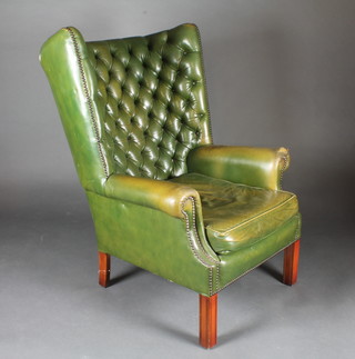 A Georgian style tub back armchair upholstered in green leather  and raised on square supports