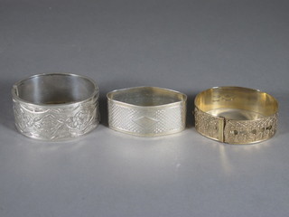 An oval engraved silver napkin ring, a silver bangle and a gilt  metal bangle