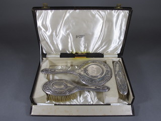 A silver 3 piece backed dressing table set comprising hair brush, hand mirror and clothes brush, cased