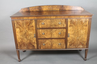 A 1930's figured walnut sideboard with raised back above 3 long drawers flanked by a pair of cupboards, raised on square tapering  supports 54"w x 41"h x 18"d