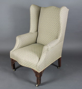 A Chippendale style winged armchair raised on fretwork supports  ILLUSTRATED