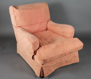 An armchair upholstered in gold coloured material with orange loose cover
